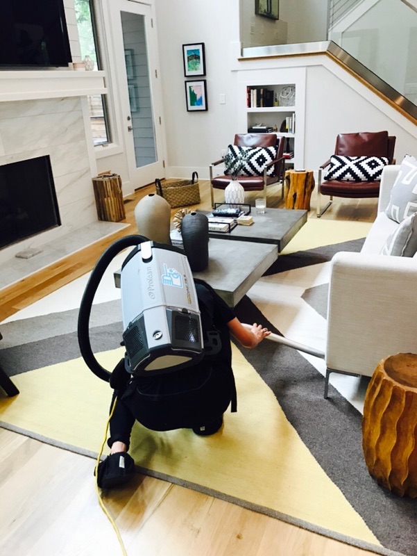 Maid Cleaning Nashville professional using a backpack vacuum in a furnished living room